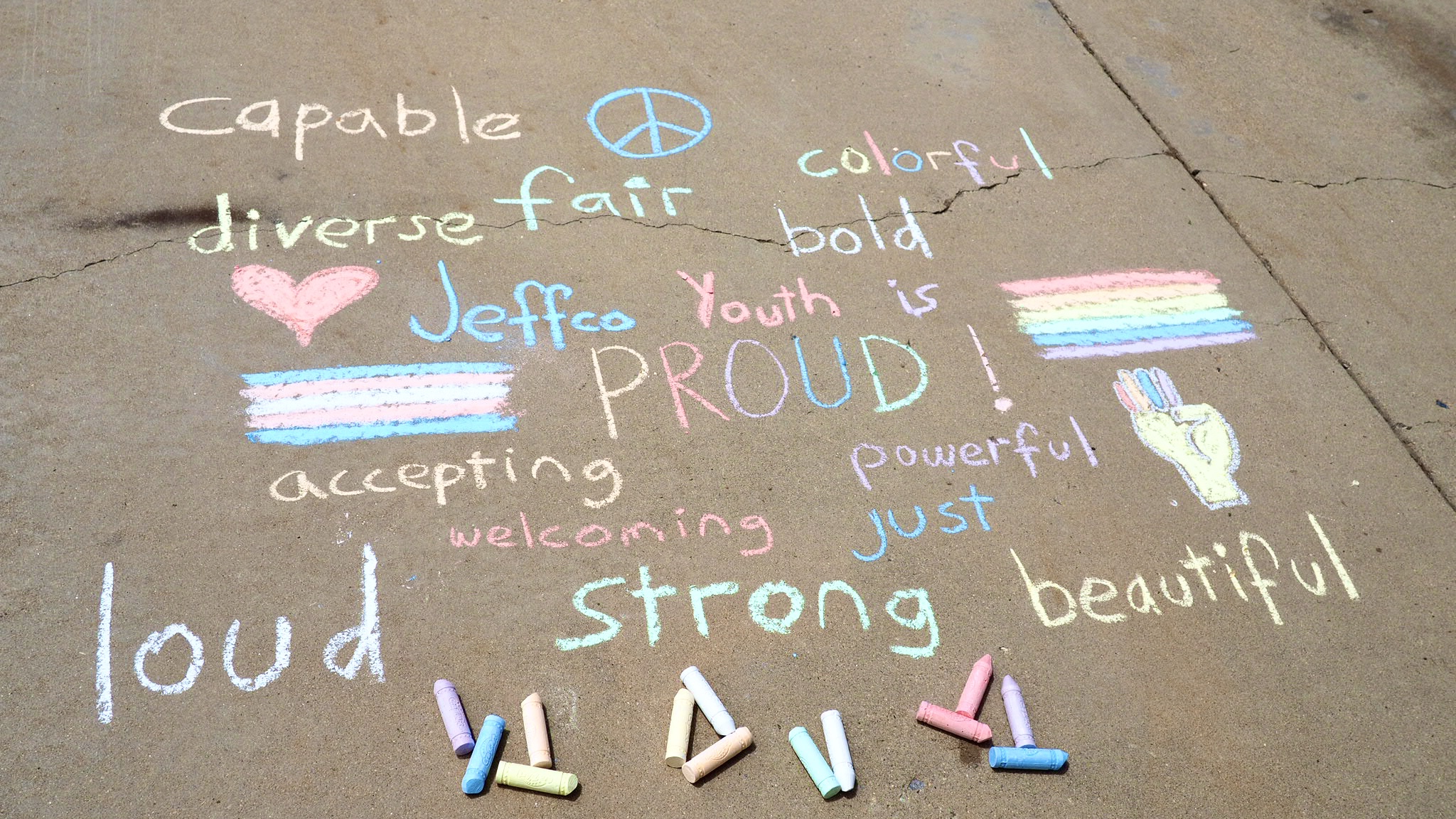 Words in multiple colors drawn in chalk on the sidewalk including: capable and diverse.