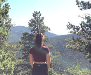 Woman on her back looking into a forest.